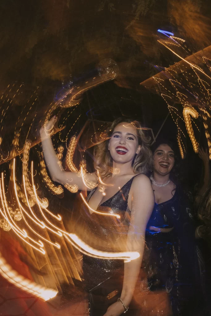 A joyful guest moves gracefully to the music, adding vibrant energy to the sangeet celebration with her dance moves.