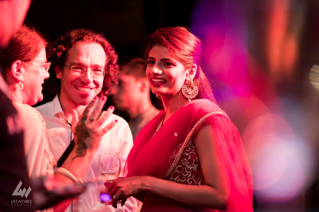 Guests engaged in conversation and laughter at a traditional Mehendi ceremony, showcasing vibrant attire and joyful expressions.