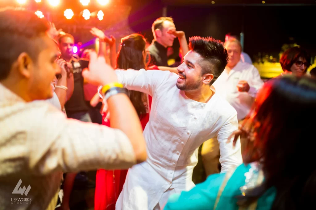 Guests joyfully dancing at a Mehendi celebration, showcasing vibrant traditional attire and lively movements as they participate in the festive event.