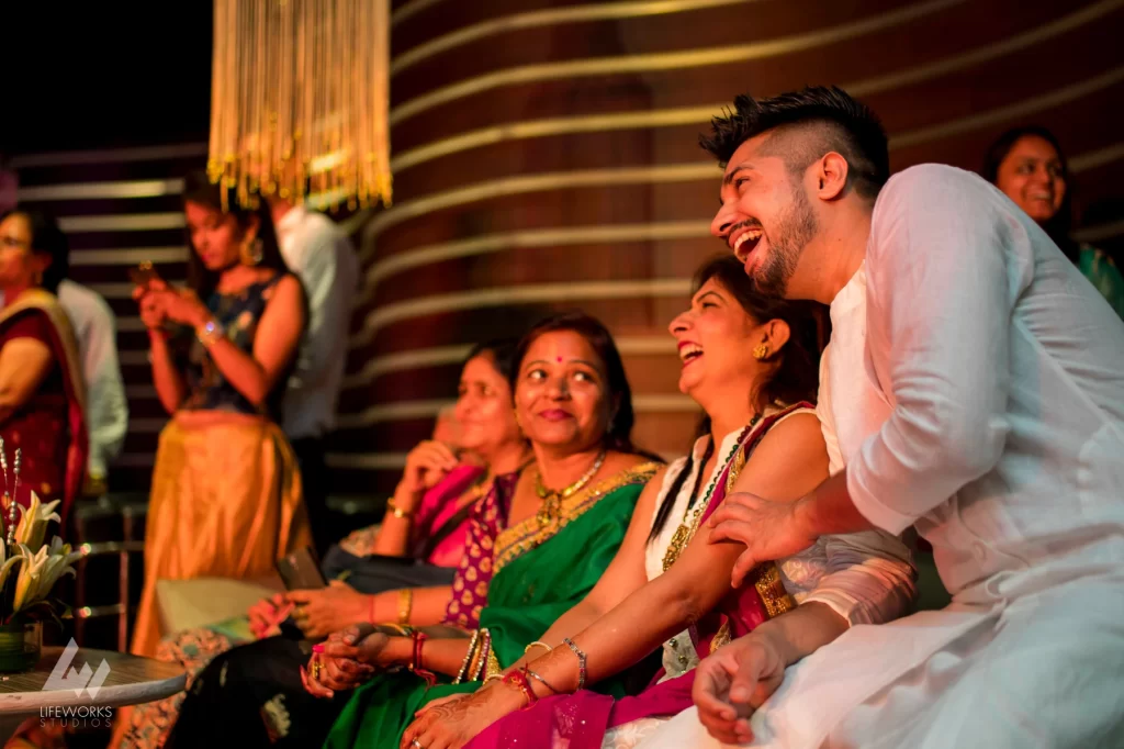 Guests at a mehendi function, laughing and enjoying themselves while participating in traditional celebrations. The atmosphere is vibrant and lively, with guests wearing colorful attire and engaging in festive activities