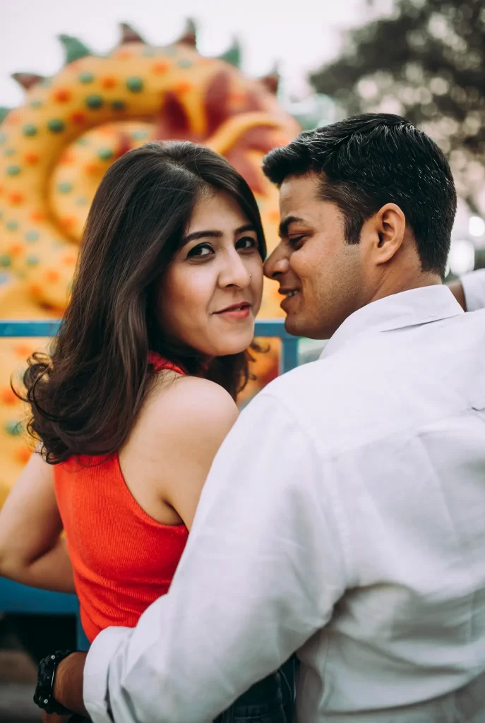 In a captivating pre-wedding moment, the groom gazes affectionately at the bride, while she is enchanted by the surrounding beauty, reflecting a sense of love and anticipation amidst a picturesque backdrop.