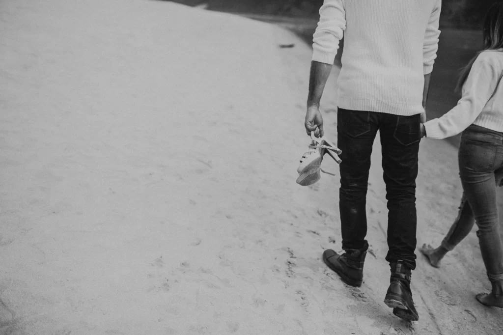 A heartwarming image captures a couple walking hand in hand, with the boy affectionately holding the heels of his girl. This gesture symbolizes care, support, and a strong emotional bond, portraying their unity and devotion to each other.