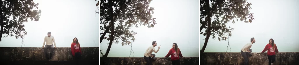 a couple sits on a stone wall near a tree, engaged in conversation. The natural and relaxed moment captures the couple's connection and the anticipation of their upcoming wedding.