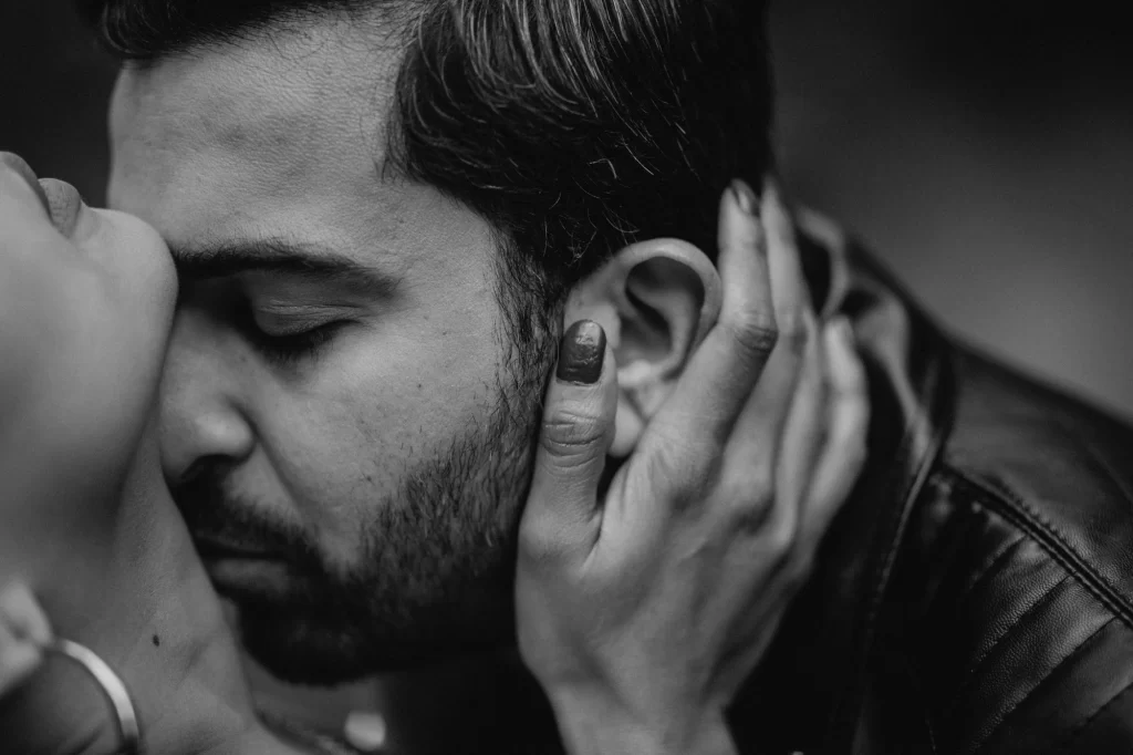 A black and white photograph capturing a couple in a romantic pre-wedding pose, exuding love and affection in an elegant monochromatic setting.