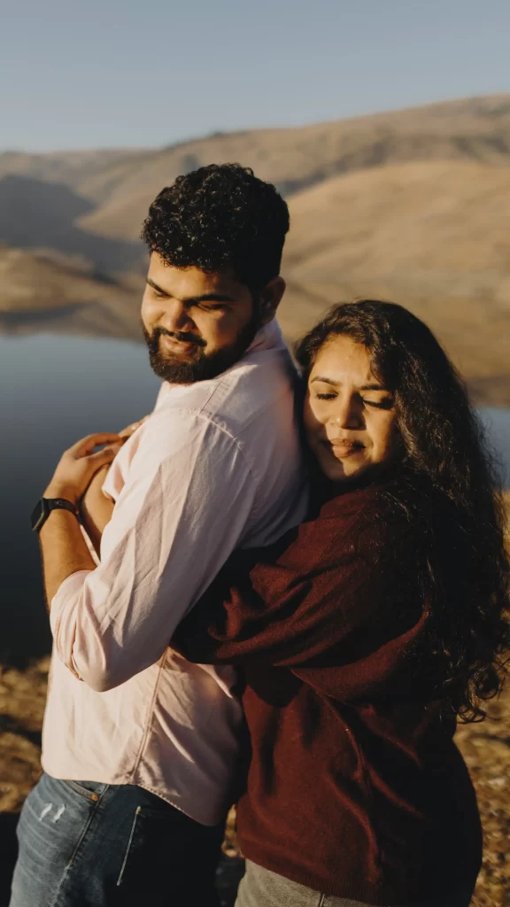 Pre-wedding photoshoot capturing a tender moment as the bride embraces her groom from behind, evoking romance and anticipation in a scenic backdrop.