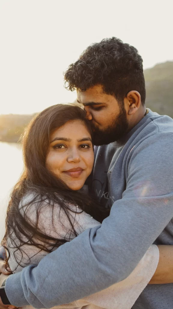 Romantic pre-wedding photoshoot moment: Groom tenderly kisses bride's forehead, encapsulating love and affection in a beautiful setting.