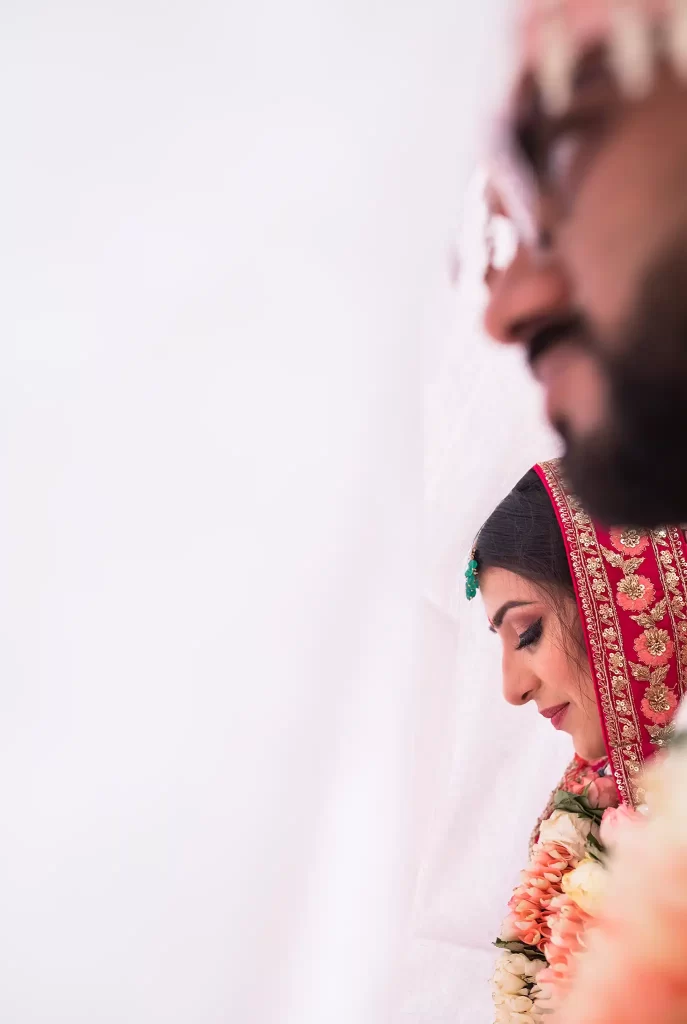 The bride and groom exchange floral garlands, known as varmala, symbolizing their union and commitment in a traditional and joyous wedding ritual.