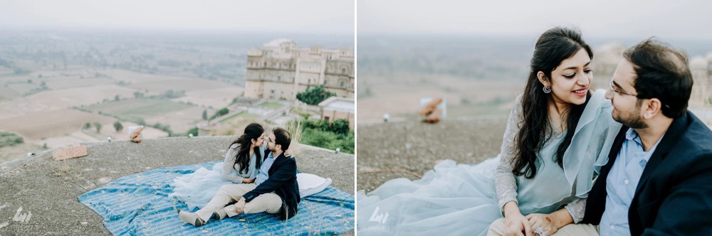  smiling couple stands embraced at the top, overlooking a stunning landscape as they pose for their pre-wedding photo shoot.