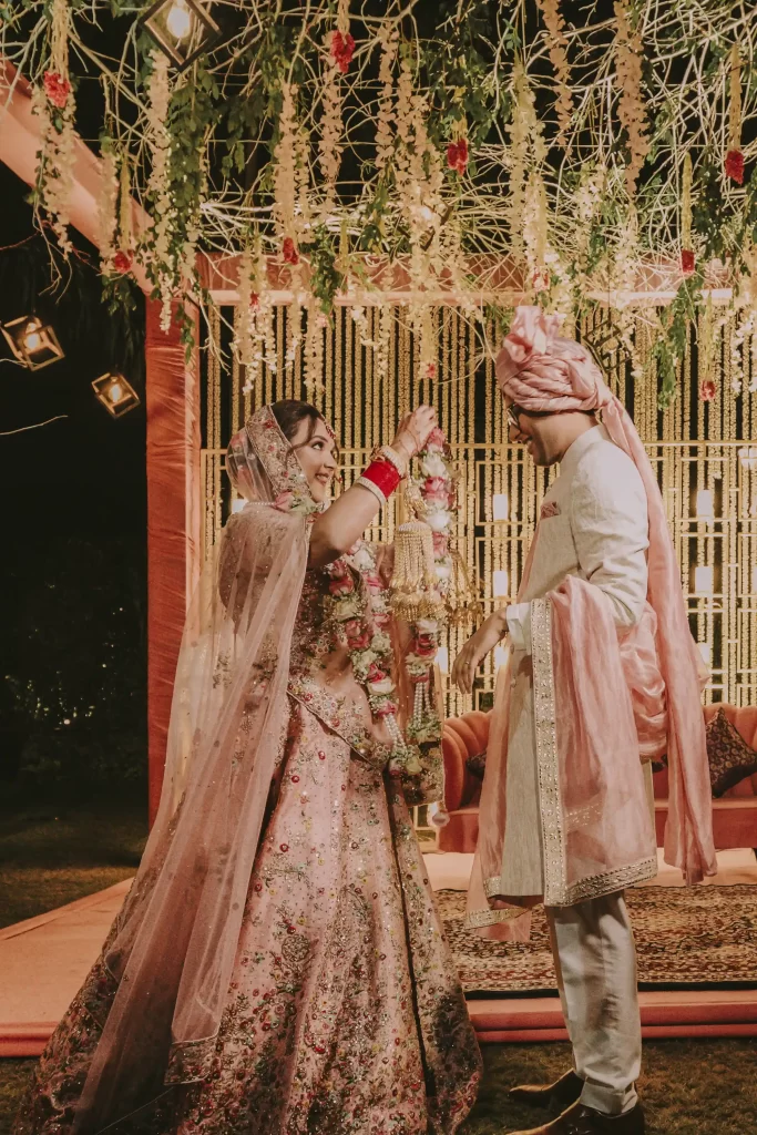 A beautiful moment as the couple adorned in traditional attire exchange varmala garlands, symbolizing their union in marriage.