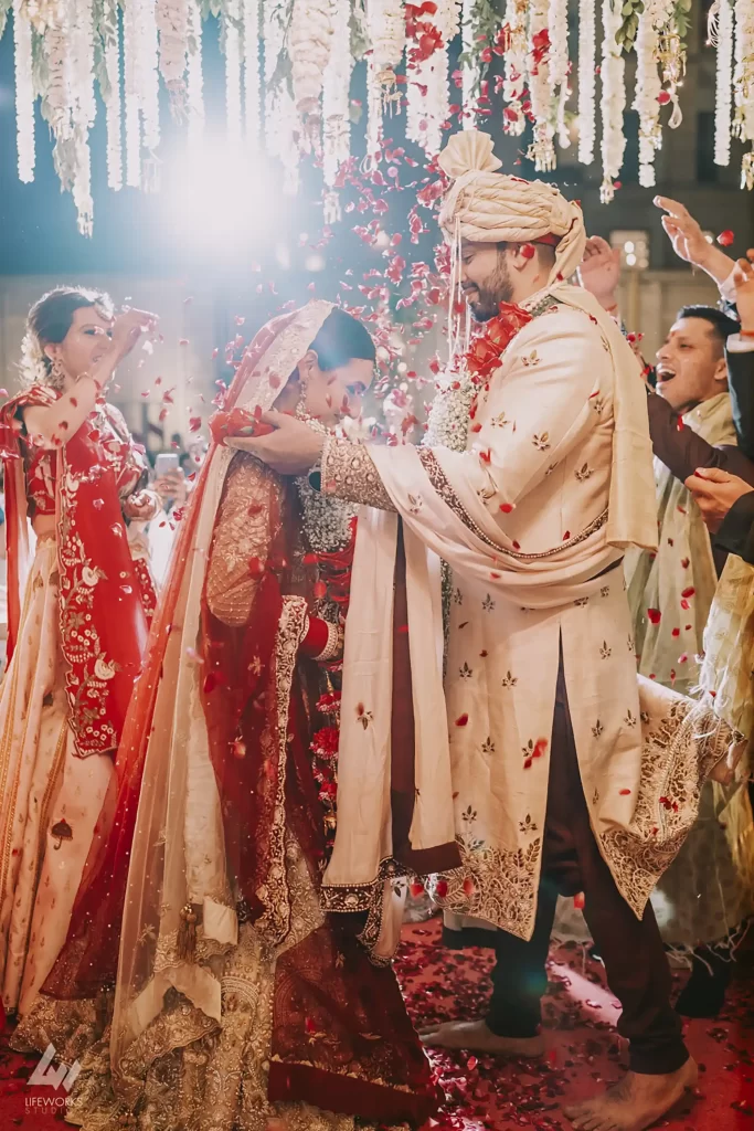 Bride and groom exchange garlands during their traditional Varmala ceremony, symbolizing their union and commitment in a joyful celebration of love and marriage.