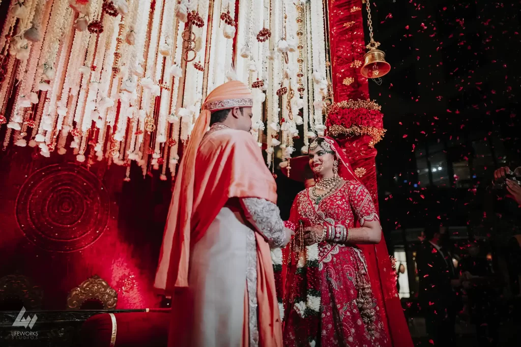 A close-up shot of a couple exchanging floral garlands during a traditional Indian wedding ceremony."