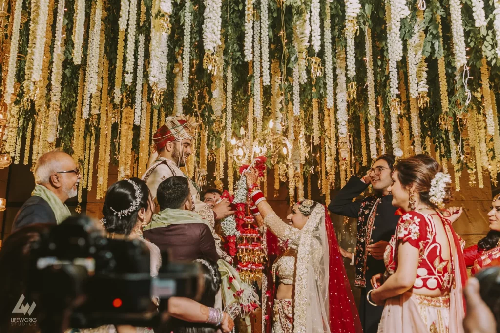 Bride and groom exchange garlands during their traditional Varmala ceremony, symbolizing their union and commitment in a joyful celebration of love and marriage.