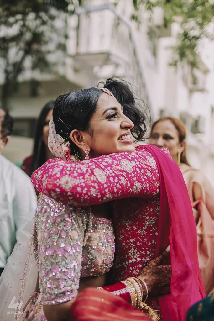 A bride clad in traditional attire embraces her mother tightly, shedding tears during the poignant bidai ceremony.