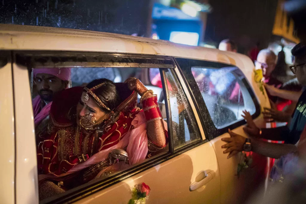  bride in traditional Indian dress is tearfully bid farewell by her family during the emotional bidai ritual.