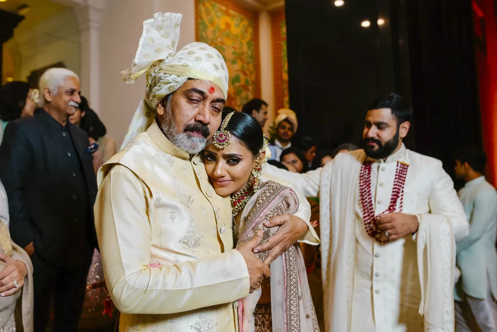 a bride clad in traditional attire embraces her father tightly, displaying emotions during the poignant bidai ceremony.