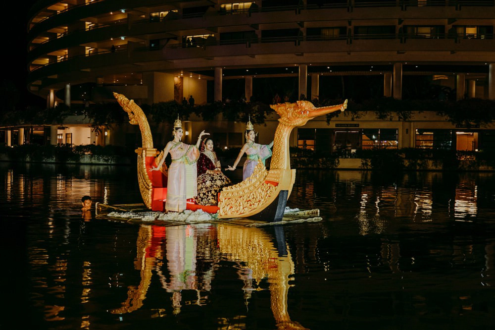 An enchanting scene of the bride, adorned in traditional Indian bridal attire, making a grand entrance onto a beautifully decorated boat.