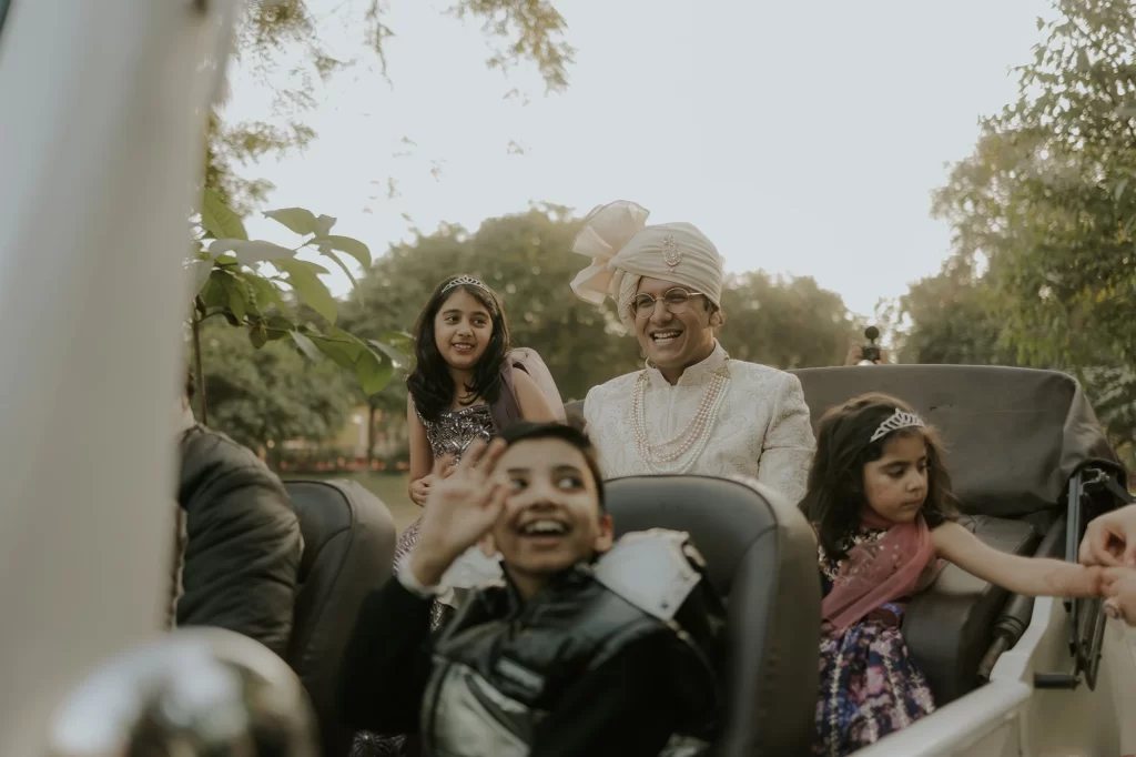  The groom joyously stands on a car, dancing fervently, as part of the traditional baraat procession during wedding celebrations.  