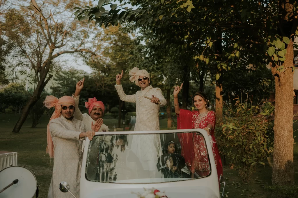  The groom joyously stands on a car, dancing fervently, as part of the traditional baraat procession during wedding celebrations.  