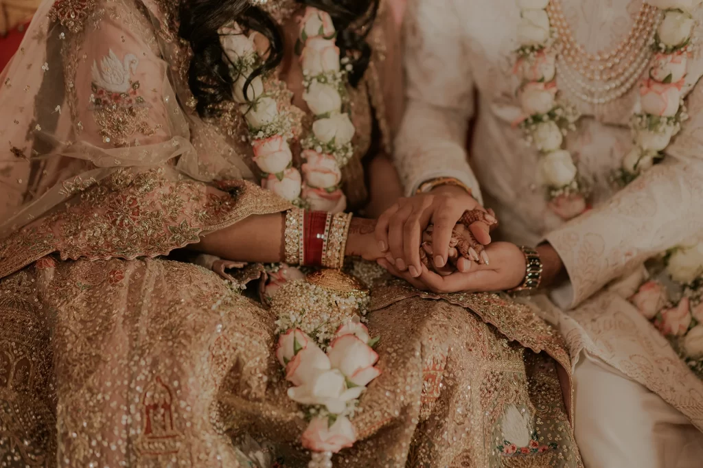  A heartfelt moment - the bride and groom clasp hands, symbolizing unity, love, and commitment during their wedding celebration.  