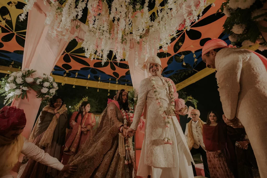 "Embracing tradition, the bride and groom partake in sacred rites at their destination wedding ceremony at Jaypee Palace, Agra, amidst grandeur.