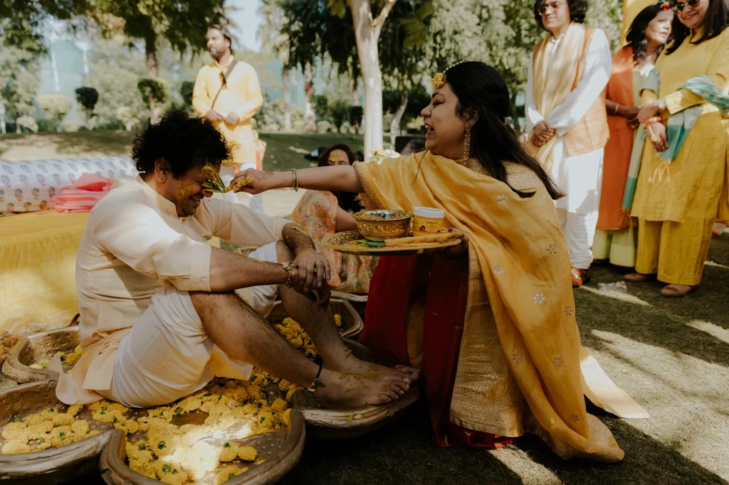  During the haldi ceremony, the groom's family joyfully apply haldi to the groom, fostering an atmosphere of celebration and camaraderie.  