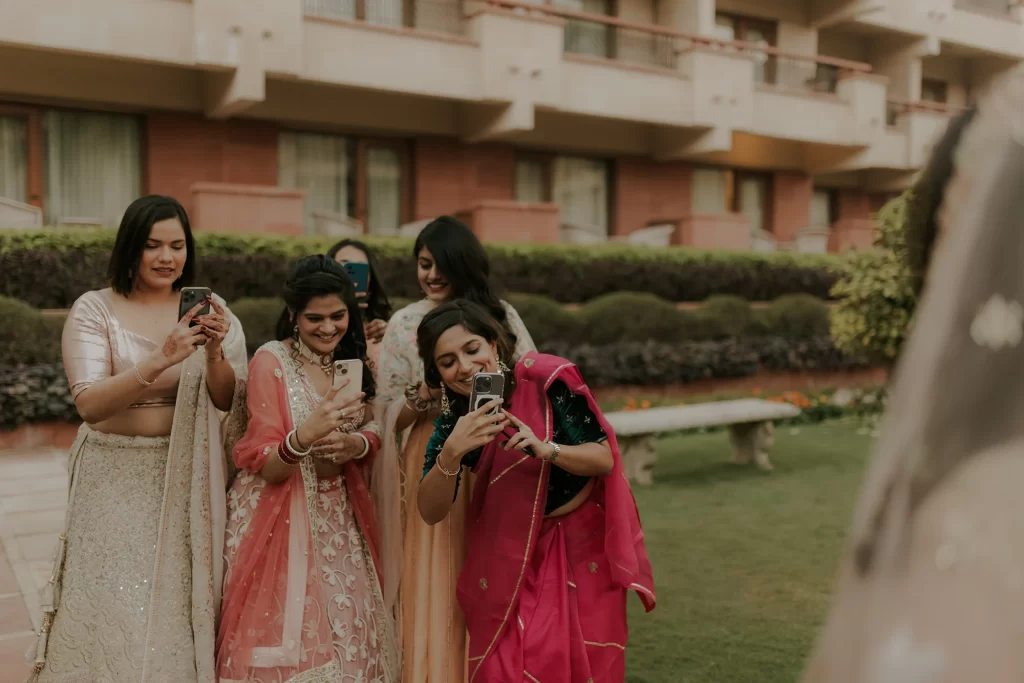  At a joyful celebration, the bride's friends capture moments with their phones, enveloping the atmosphere with warmth and camaraderie.  