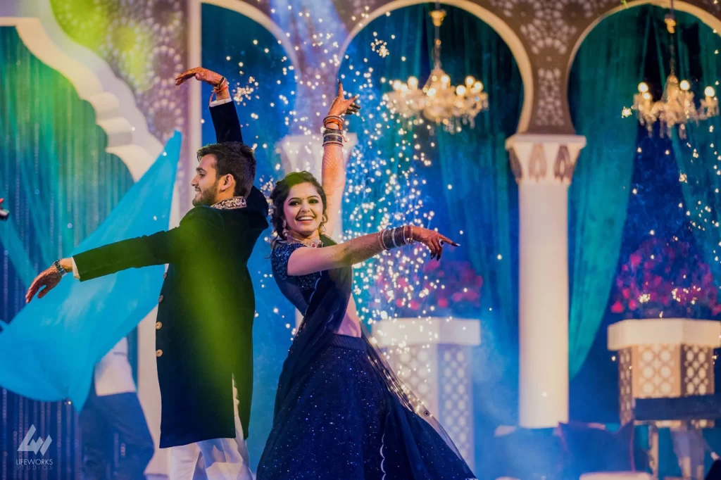 The bride and groom joyfully dance during their sangeet, expressing happiness, love, and a lively celebration of their union.