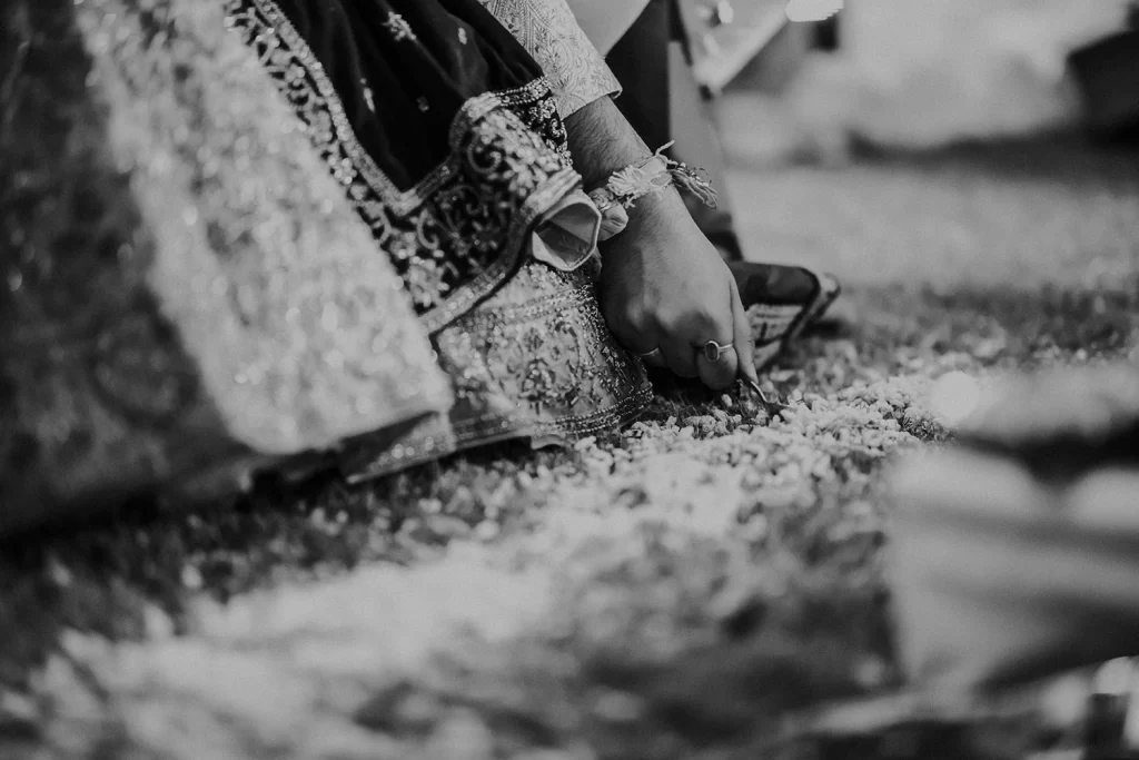 The bride and groom engage in traditional Indian rituals, adorned in ceremonial attire, symbolizing union, love, and cultural customs