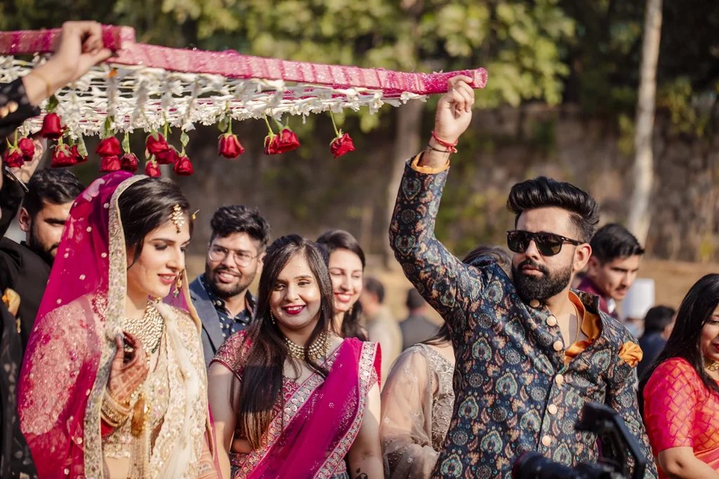 A stunning bride in traditional Indian attire, adorned with intricate jewelry, entering a The Grand, wedding venue for her destination wedding.