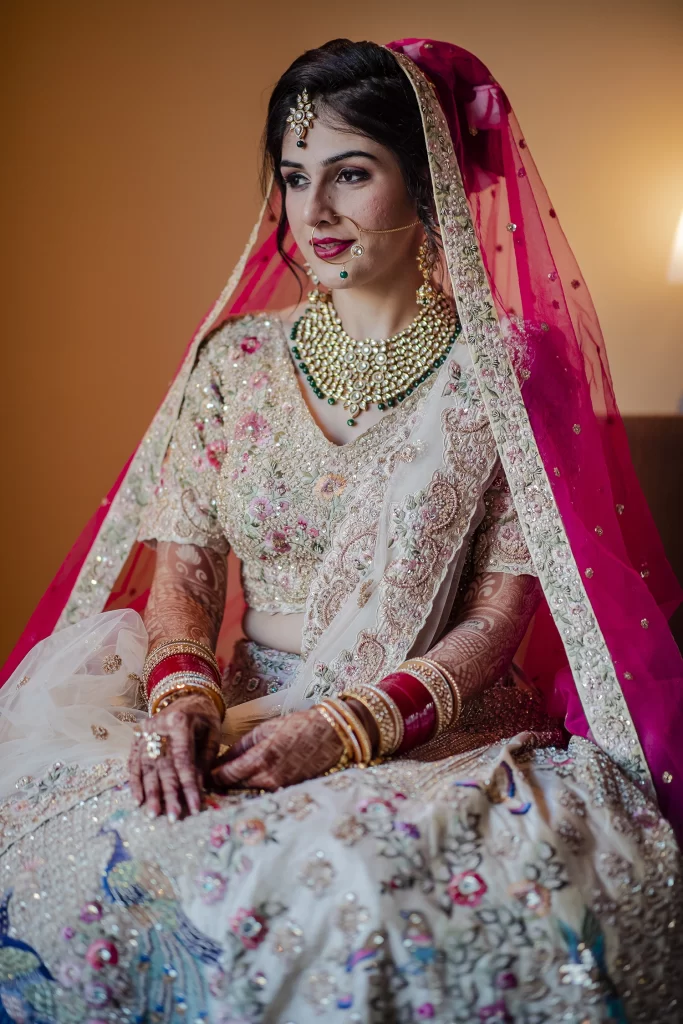 Indian bride radiates beauty and charm during a photo session showcasing her exquisite destination wedding attire at The Grand in Delhi.