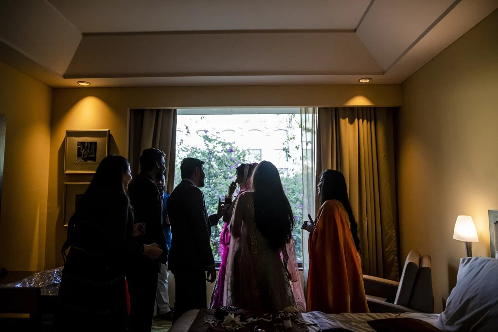 Vibrant image of Indian bride enjoying candid moments with brother, friends, and sister post getting ready for wedding.