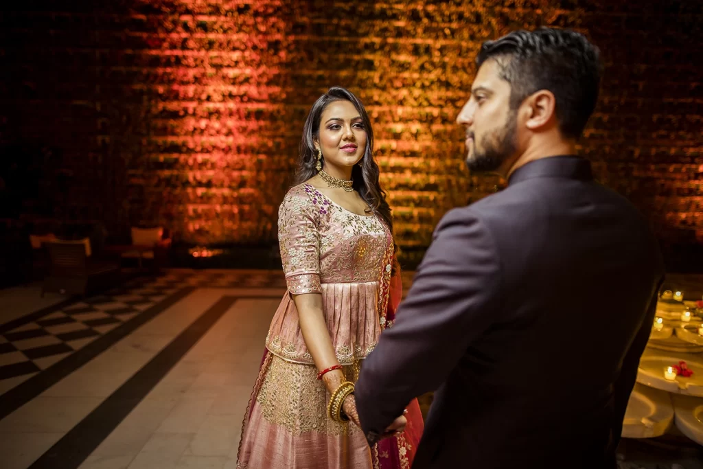 A couple standing in a candid moment at The Oberoi, Delhi, captured in a romantic embrace, smiling and happy.