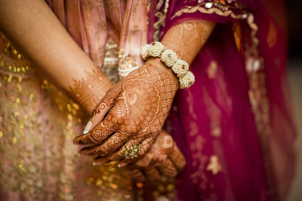 A bride's hand adorned with intricate jewellery and mehendi, capturing the cultural beauty and elegance of her wedding preparations.