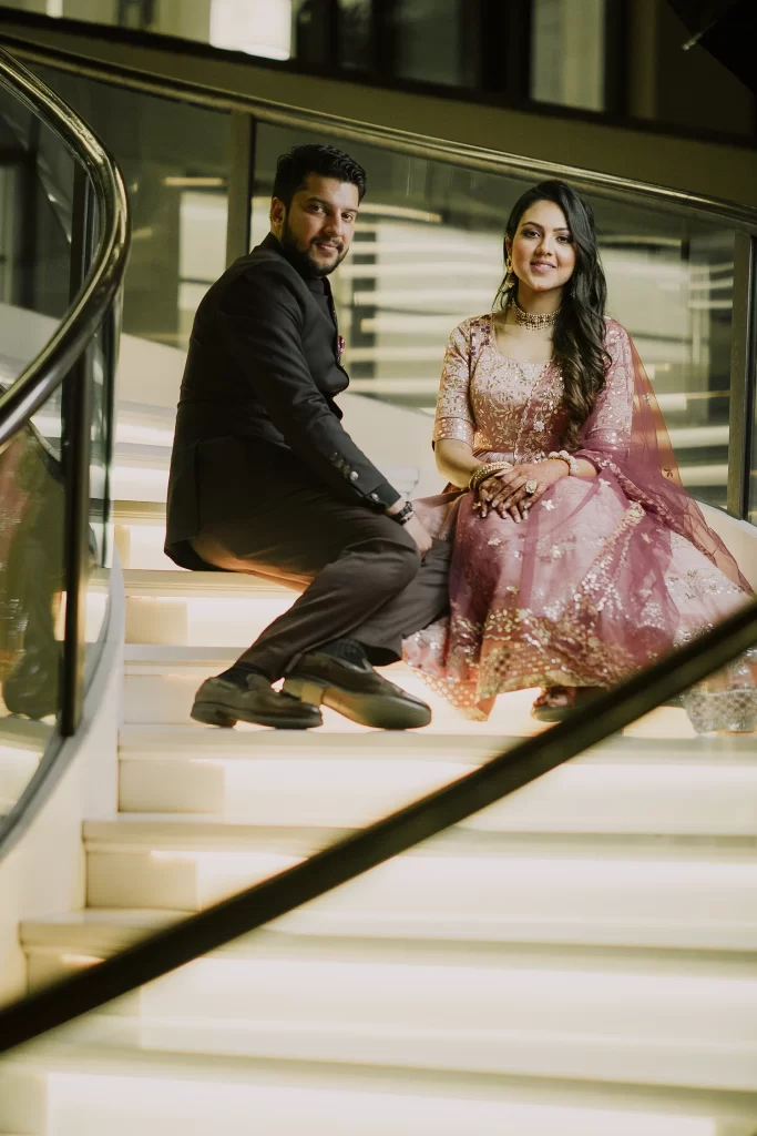 A couple sits gracefully on the elegant staircase for their photo session at The Oberoi, exuding timeless romance and charm