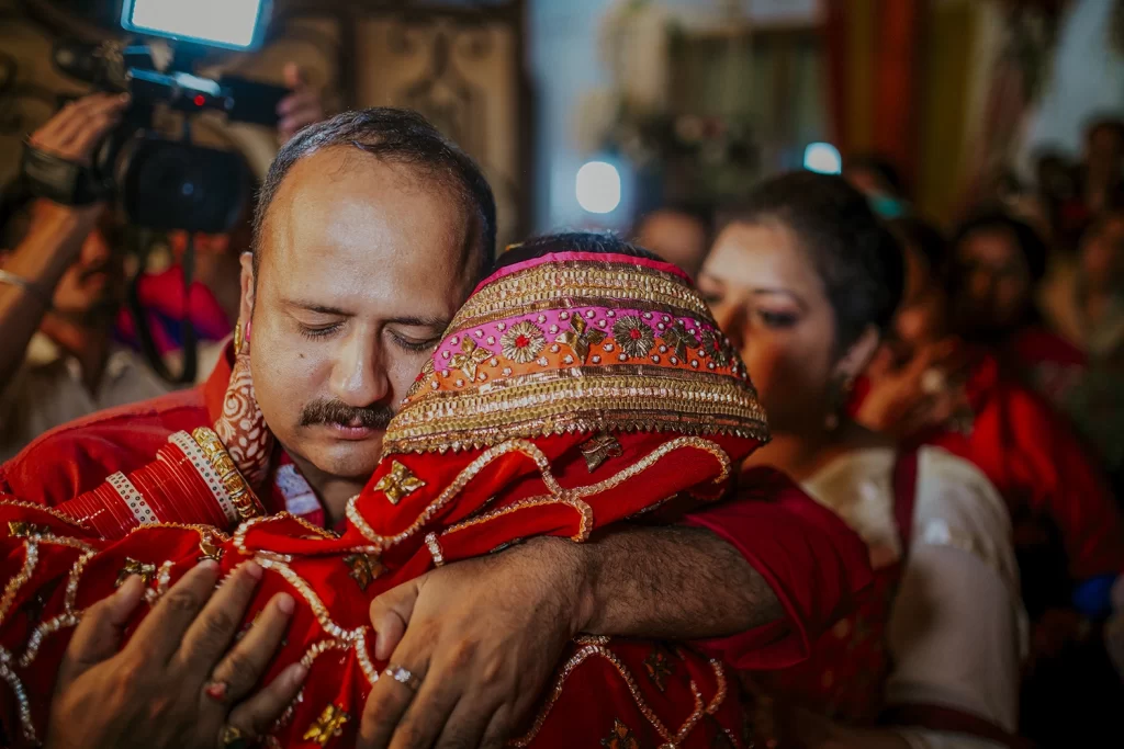 Tearful bride embracing her father at bidai, expressing love and gratitude in a poignant moment before beginning her new journey.