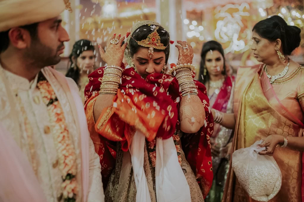 A bride in traditional attire bids an emotional farewell, surrounded by loved ones, capturing the poignant moment with grace.