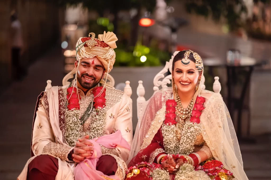 The bride and groom, radiating happiness and love, stand together on their wedding day, dressed in elegant attire and smiles.