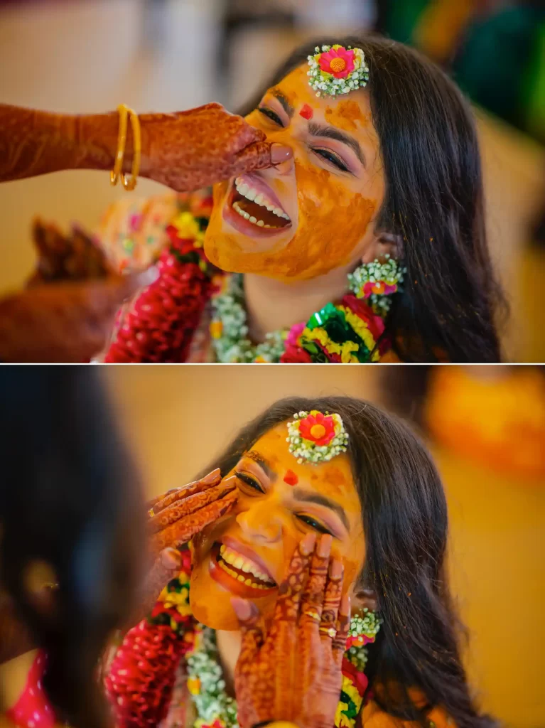 A bride smiling as her family and friends apply haldi paste on her face during the pithi ceremony