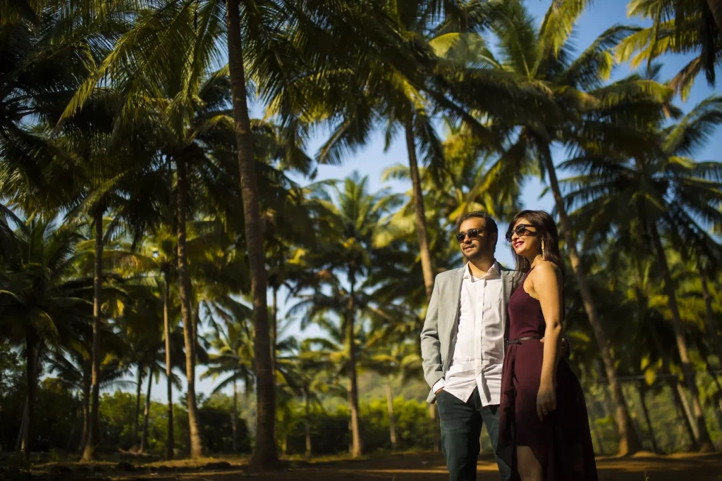 Couple sharing happy moments and surrounded by lush palm trees during their pre-wedding shoot in Goa.
