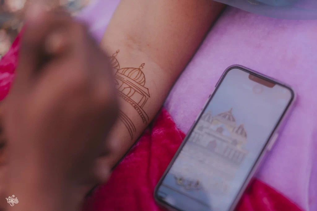 A skilled artist carefully applying intricate mehndi patterns on a bride's hand at a mehndi ceremony.