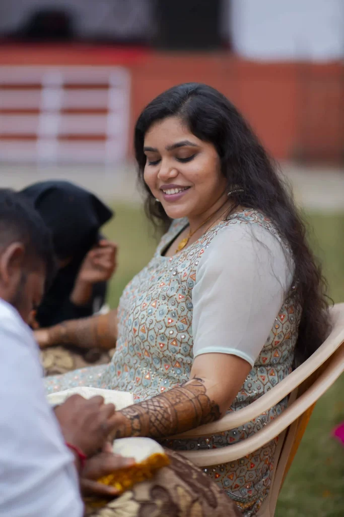 The bride getting intricate mehndi designs applied to her hands.
