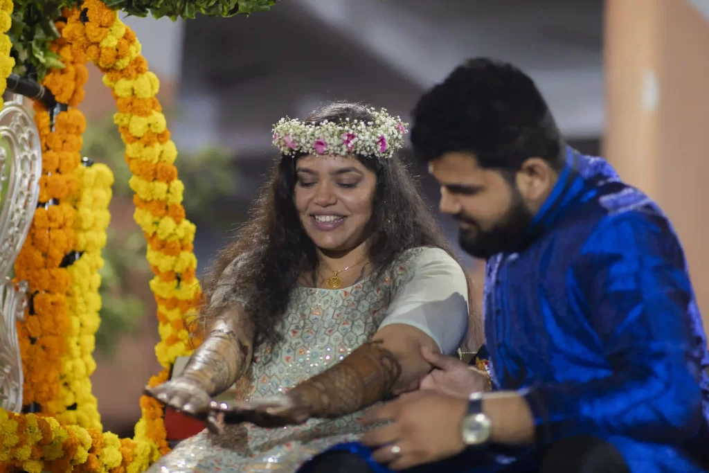 Groom playfully searches for his name within the bride's intricate mehndi design, as joyful Mehndi songs for wedding play.