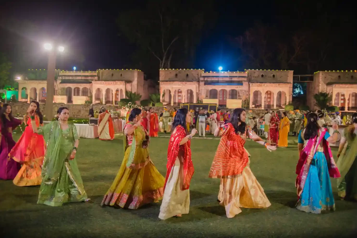 view of wedding guests celebrating at Neemrana, surrounded by historic architecture and lush gardens.
