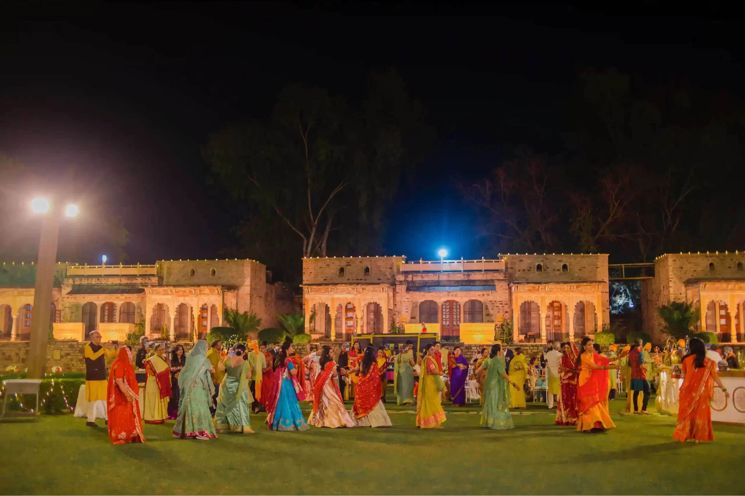 view of wedding guests celebrating at Neemrana, surrounded by historic architecture and lush gardens.
