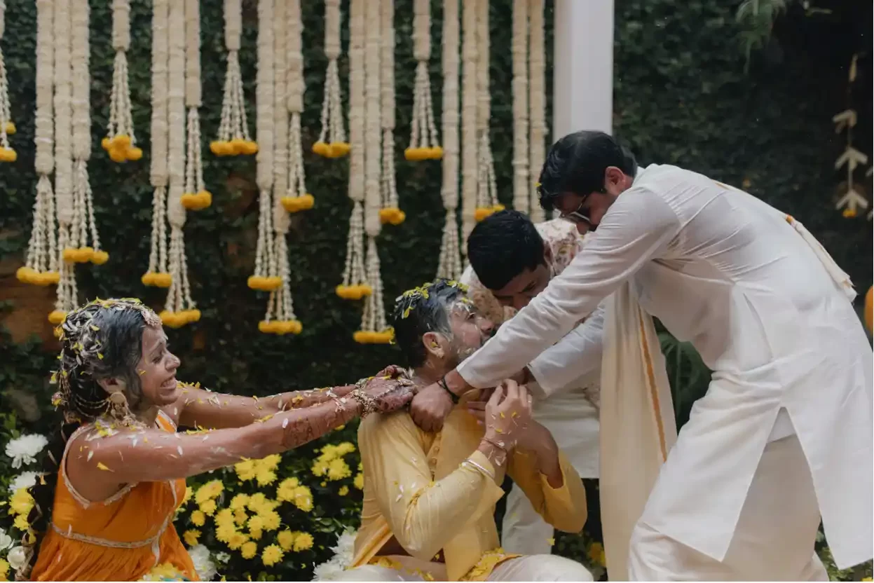 Friends and the bride playfully try to tear the groom's clothes at the haldi ceremony during this joyous Hindu wedding in Dubai.