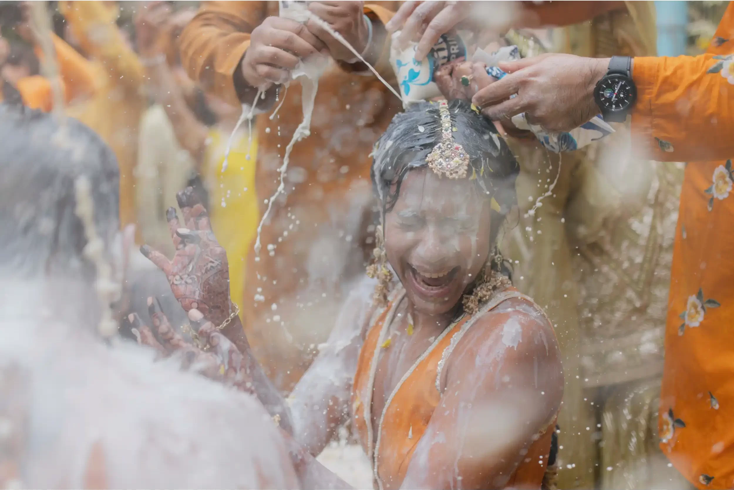 During a Hindu wedding in Dubai, participants joyfully throw milk at the bride and groom during the lively haldi ceremony.