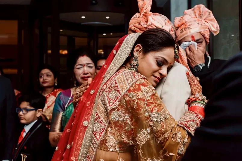The bride and her father share tears during her bidaai, encapsulating the bittersweet emotions of this significant farewell moment.