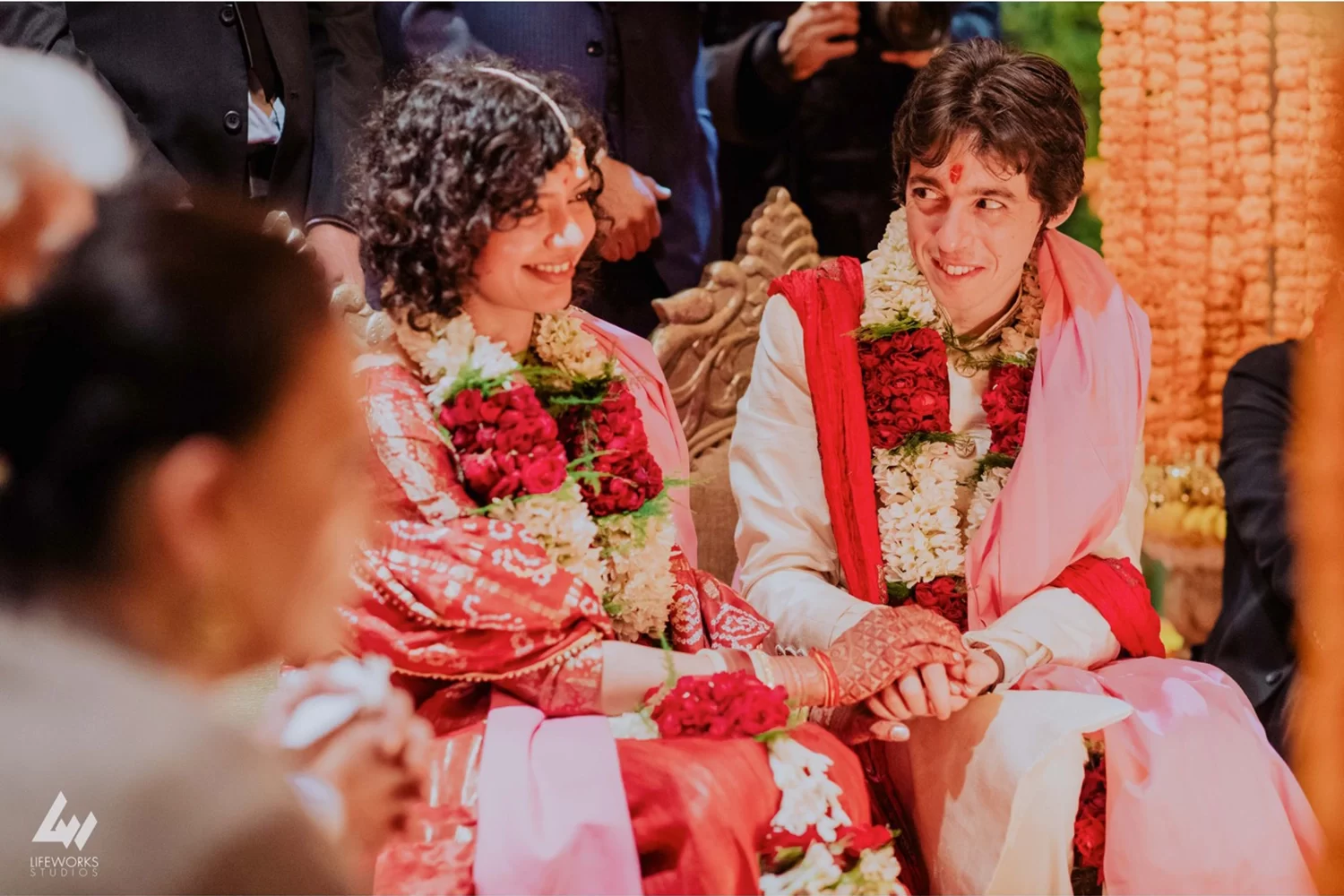 The bride and groom sit together at the mandap, immersed in love and tradition during their beautiful wedding ceremony.