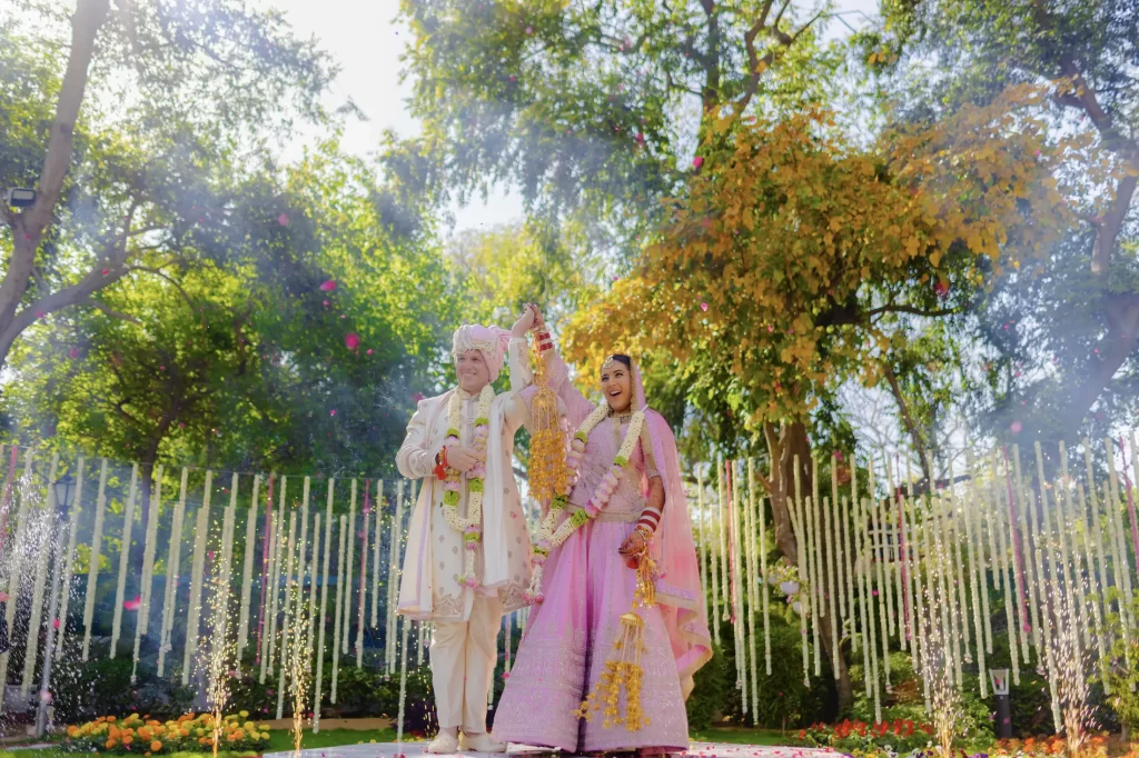 Wedding photography in AbuDhabi captures a joyful moment as the couple celebrates with varmala and a beautiful flower shower.