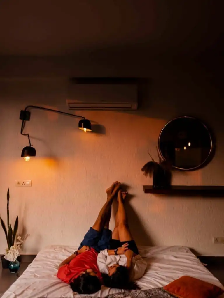 A couple poses affection in their cozy home for a pre-wedding shoot, surrounded by natural light and warm decor.